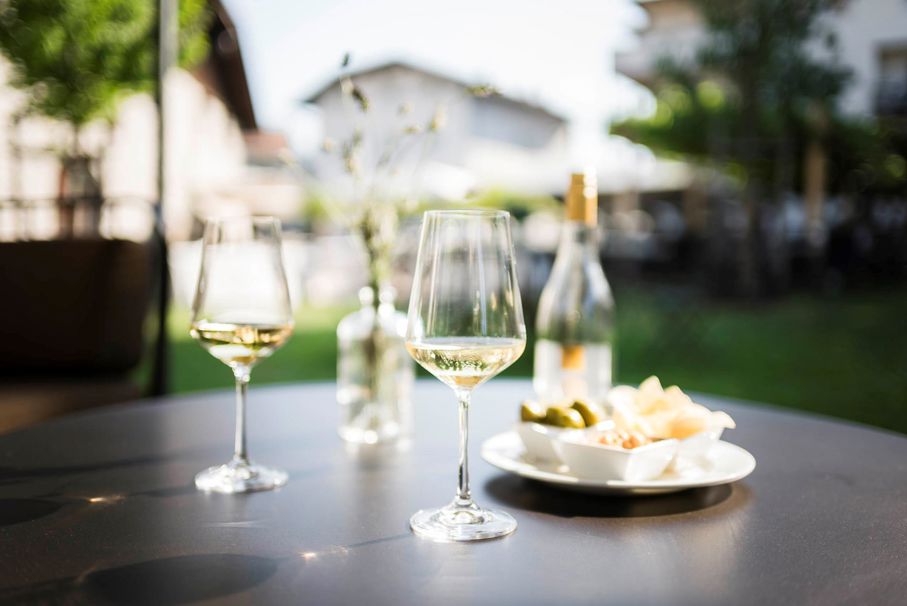 Zwei Gläser mit Weiswein und einige Häppchen auf einem Tisch im Garten